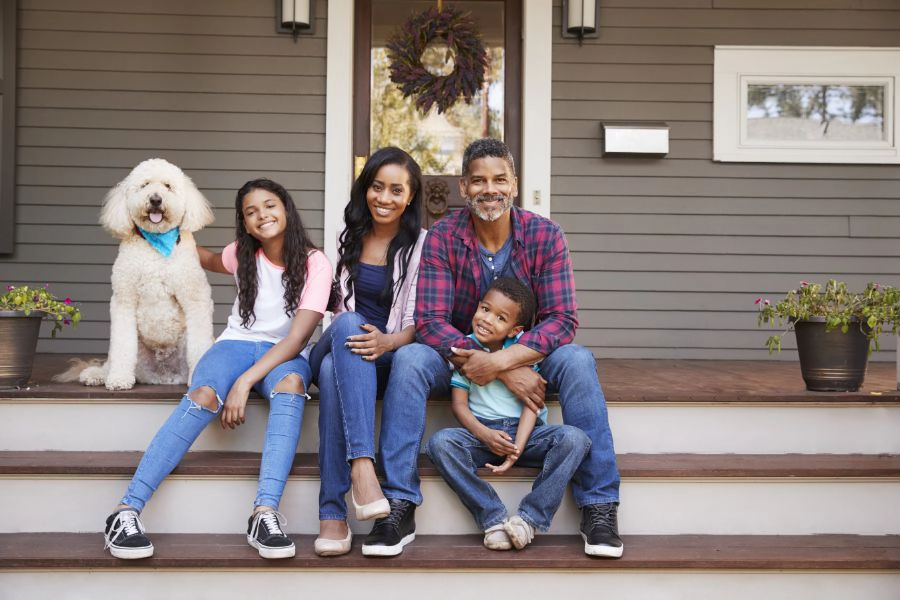 A family of four sitting on the porch of their home - Keep termites away from your home with with SOS Exterminating in Gilbert AZ